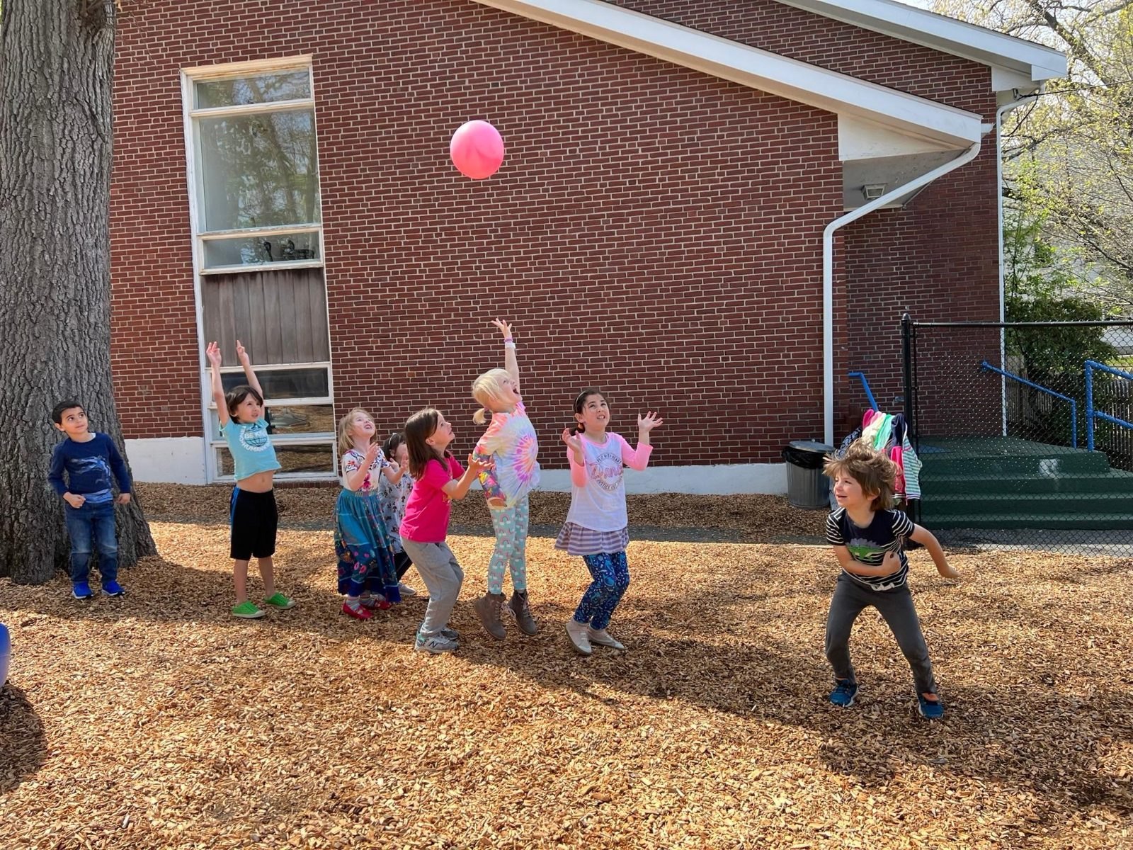 Preschoolers playing ball together outdoors at Auburndale Community Nursery School in Newton, MA